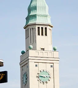 Turm mit einer grünen Kuppel und einem Ziffernblatt, das die Uhrzeit anzeigt.