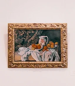 Gemälde eines Stilllebens mit einem Krug und einer Obstschale auf einem Tisch.